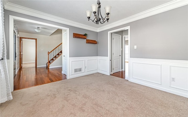 spare room with an inviting chandelier, crown molding, and carpet floors