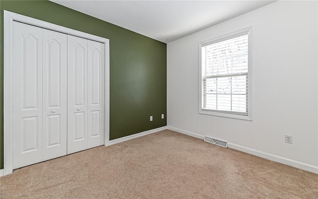 unfurnished bedroom with a closet and light carpet