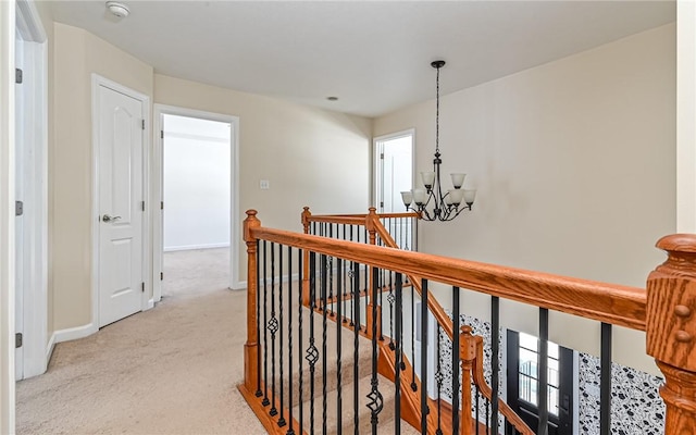 hallway featuring an inviting chandelier and light colored carpet