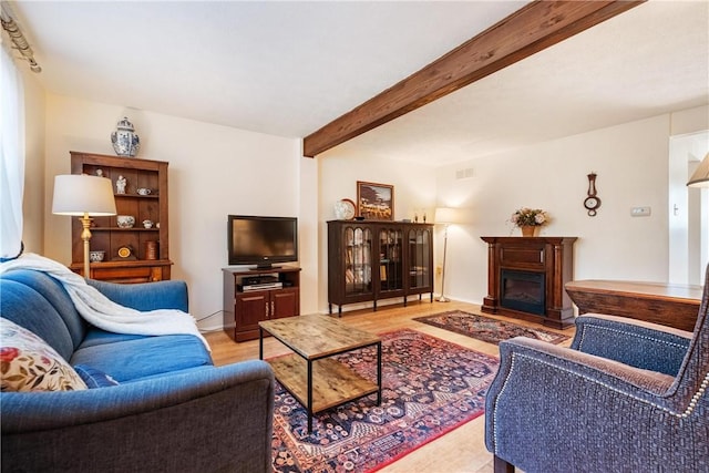 living room featuring beamed ceiling and a fireplace