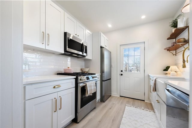 kitchen featuring white cabinets, appliances with stainless steel finishes, light hardwood / wood-style floors, and tasteful backsplash