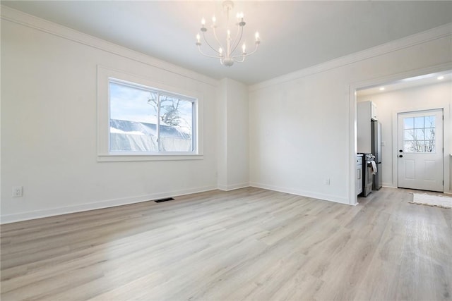 unfurnished room featuring ornamental molding, light wood-type flooring, a healthy amount of sunlight, and a notable chandelier