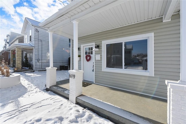 snow covered property entrance featuring a porch