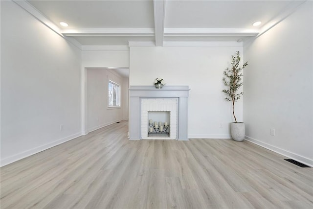 unfurnished living room with a brick fireplace, light wood-type flooring, and beam ceiling