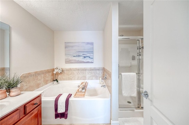 bathroom with a textured ceiling, independent shower and bath, and vanity