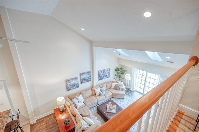 living room featuring lofted ceiling with skylight and hardwood / wood-style flooring