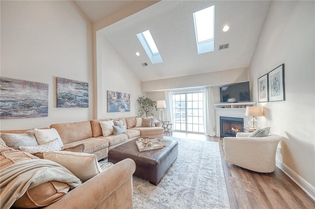 living room featuring high vaulted ceiling, a skylight, and light hardwood / wood-style flooring