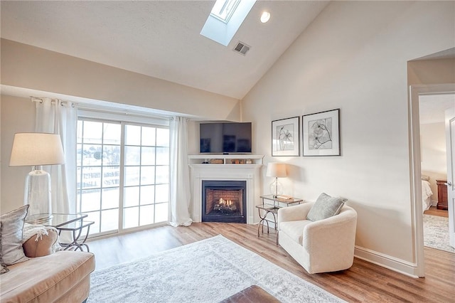 living room featuring light wood-type flooring and lofted ceiling with skylight