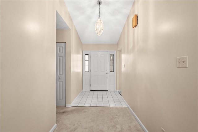 foyer entrance featuring light colored carpet and an inviting chandelier