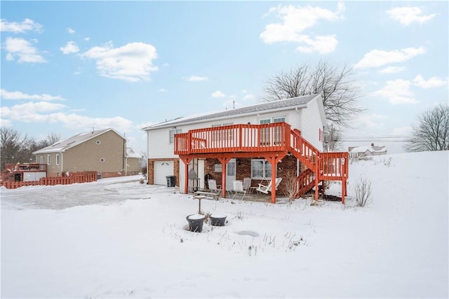 snow covered back of property featuring a deck and a garage