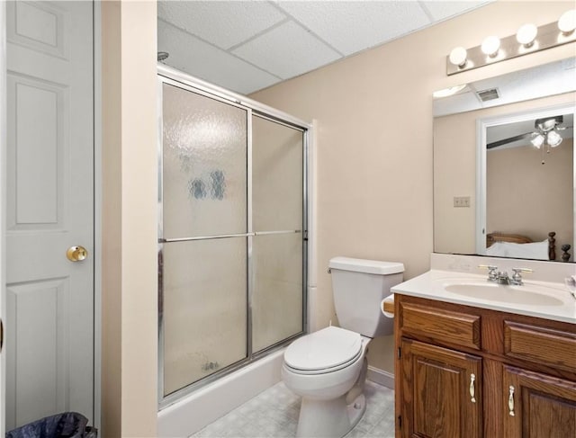 bathroom featuring toilet, a paneled ceiling, ceiling fan, a shower with shower door, and vanity