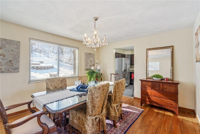 dining area with hardwood / wood-style floors and an inviting chandelier