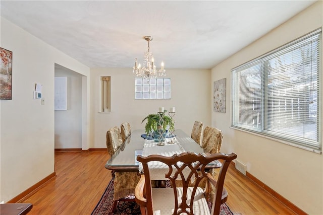 dining space featuring light wood-type flooring and a chandelier