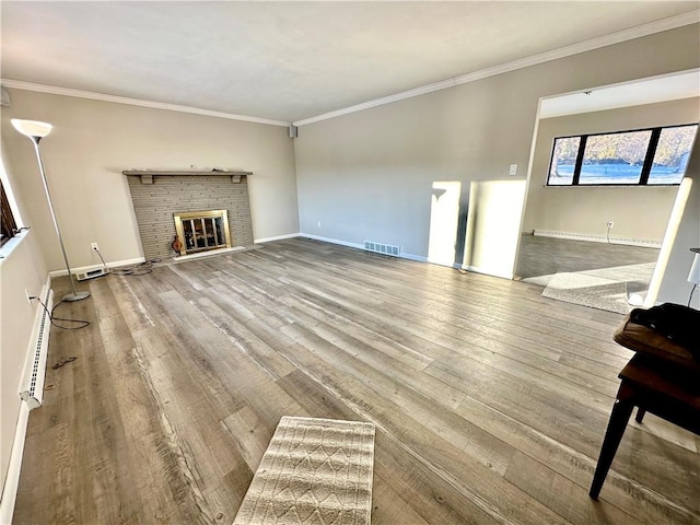 unfurnished living room with a brick fireplace, ornamental molding, and wood-type flooring