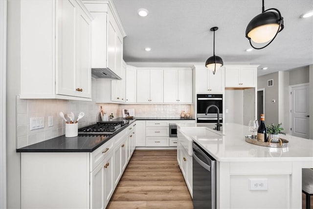 kitchen with hanging light fixtures, appliances with stainless steel finishes, sink, and white cabinets