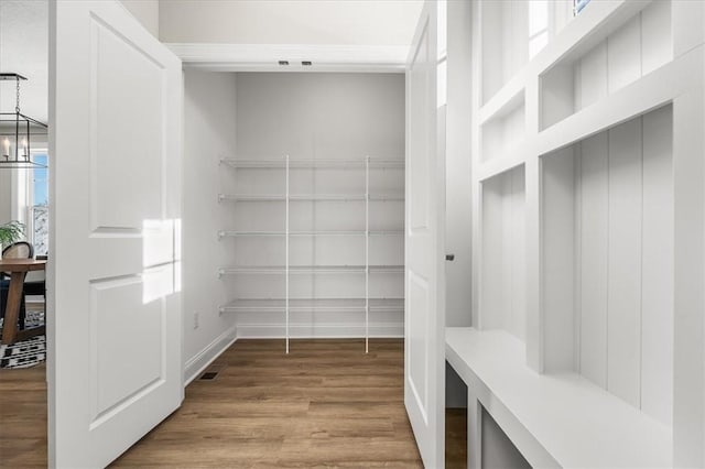 walk in closet featuring a notable chandelier and light hardwood / wood-style flooring