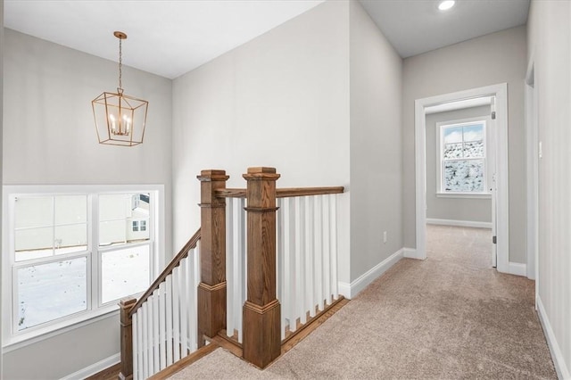 hallway with light carpet and a chandelier