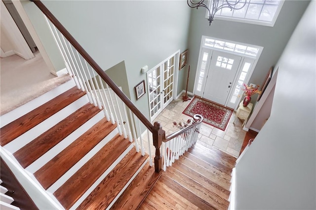 foyer with a notable chandelier, a healthy amount of sunlight, and a high ceiling