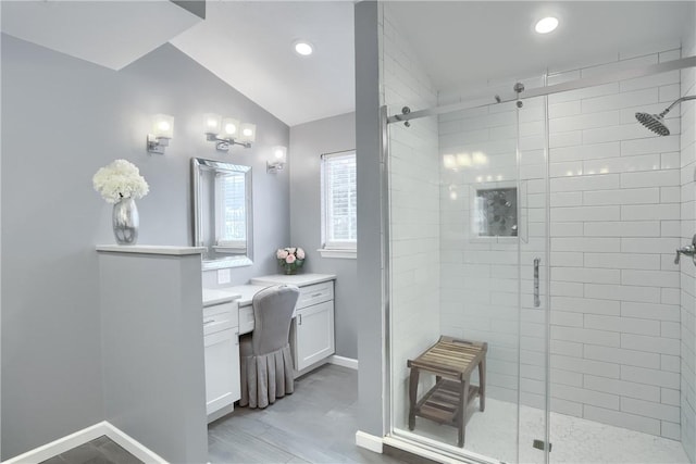 bathroom featuring vanity, a shower with shower door, and lofted ceiling