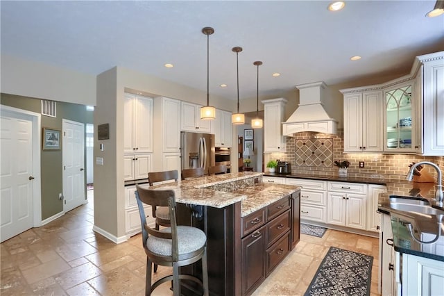 kitchen with sink, a center island, appliances with stainless steel finishes, a kitchen breakfast bar, and custom range hood