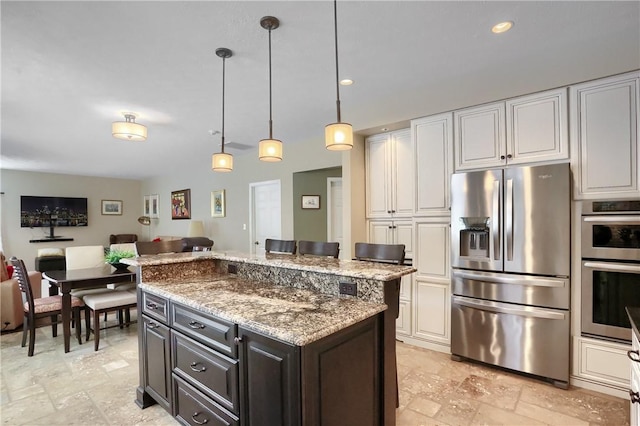 kitchen featuring a kitchen island, appliances with stainless steel finishes, decorative light fixtures, white cabinets, and light stone counters