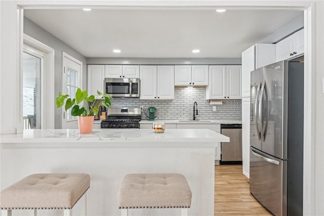 kitchen with stainless steel appliances, a kitchen bar, white cabinetry, and kitchen peninsula