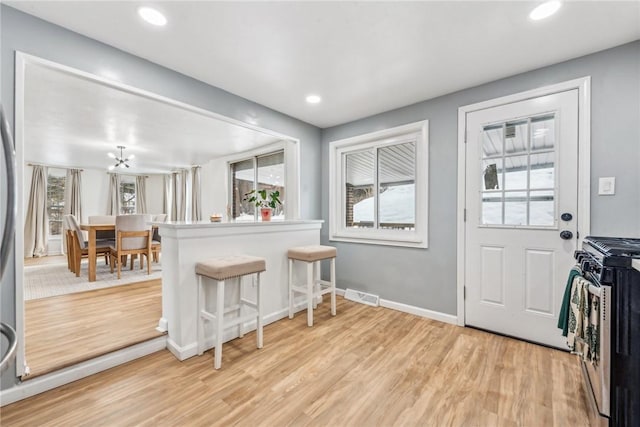 interior space with a notable chandelier, light hardwood / wood-style floors, and plenty of natural light