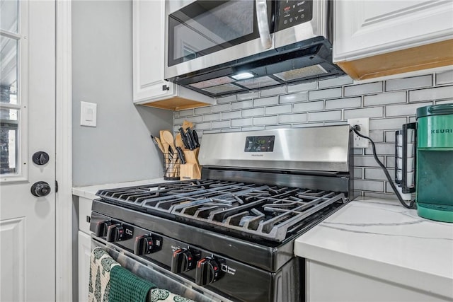 kitchen featuring light stone countertops, appliances with stainless steel finishes, tasteful backsplash, and white cabinetry