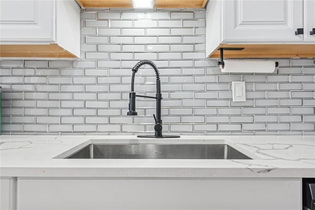 room details featuring white cabinets, decorative backsplash, and light stone countertops