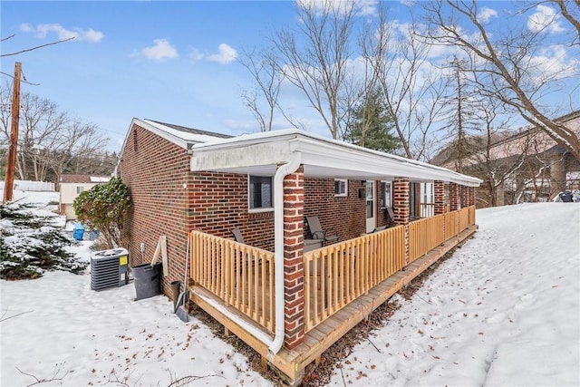 view of snowy exterior with a porch and central AC unit