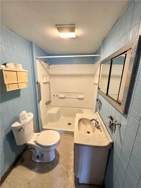 bathroom featuring toilet, a shower, and vanity