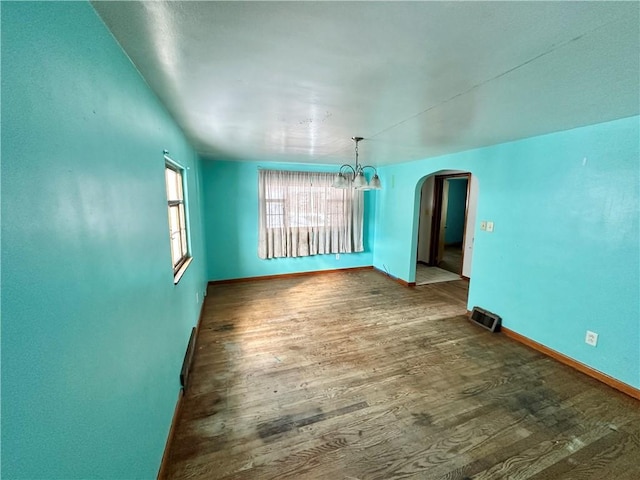 spare room with an inviting chandelier and dark hardwood / wood-style floors