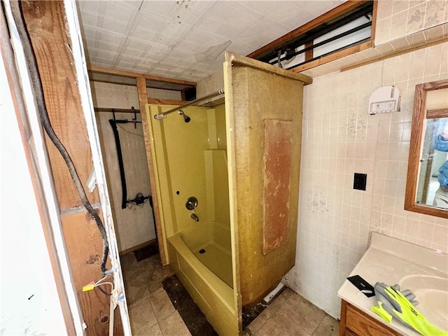 bathroom featuring tile walls, tile patterned flooring,  shower combination, and vanity