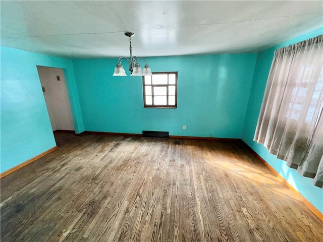 unfurnished dining area featuring a notable chandelier and dark hardwood / wood-style flooring