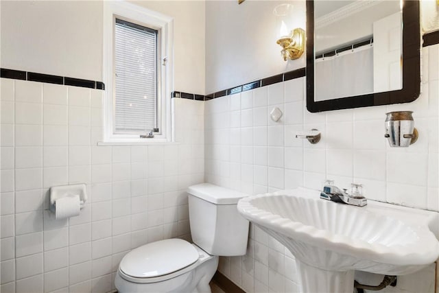 bathroom with tile walls, ornamental molding, sink, and toilet