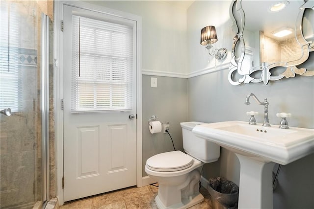 bathroom featuring toilet, a shower with door, and a healthy amount of sunlight