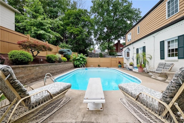 view of swimming pool with a patio and a diving board