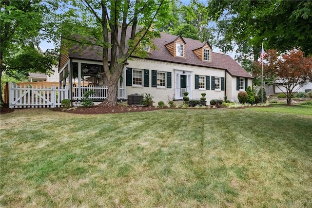 cape cod house featuring cooling unit and a front lawn