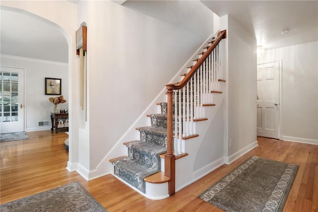 stairway featuring ornamental molding and wood-type flooring