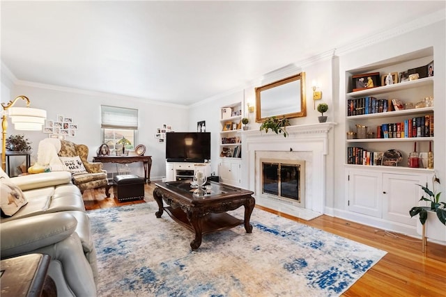 living room with crown molding, built in shelves, and wood-type flooring