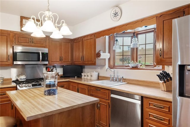 kitchen with wooden counters, stainless steel appliances, a center island, sink, and decorative light fixtures