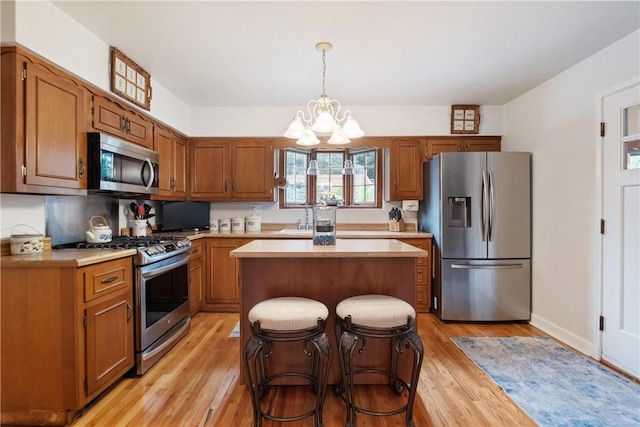 kitchen featuring stainless steel appliances, a center island, a chandelier, and light hardwood / wood-style floors