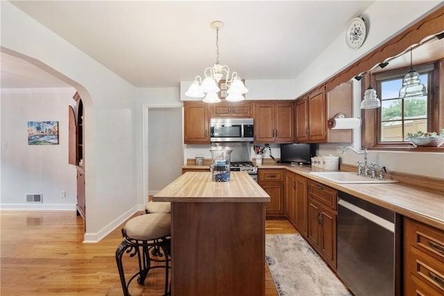 kitchen featuring sink, a center island, wood counters, a breakfast bar area, and appliances with stainless steel finishes