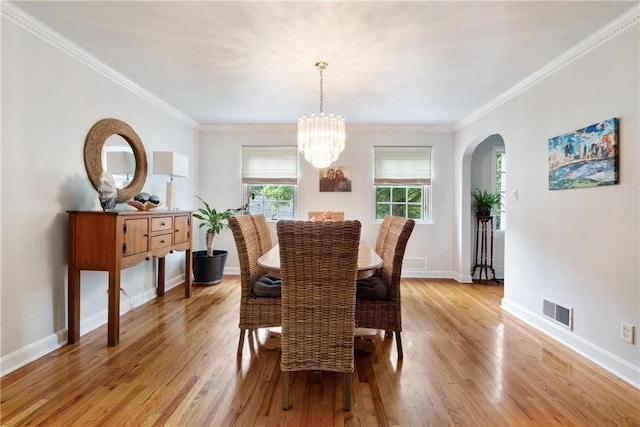 dining area featuring light hardwood / wood-style flooring, crown molding, and a chandelier