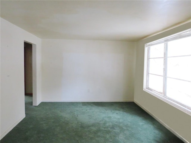 carpeted empty room featuring baseboards