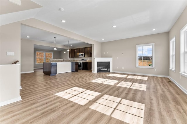 unfurnished living room featuring sink and light wood-type flooring