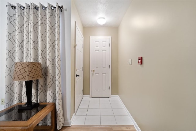 doorway featuring light tile patterned flooring and a textured ceiling