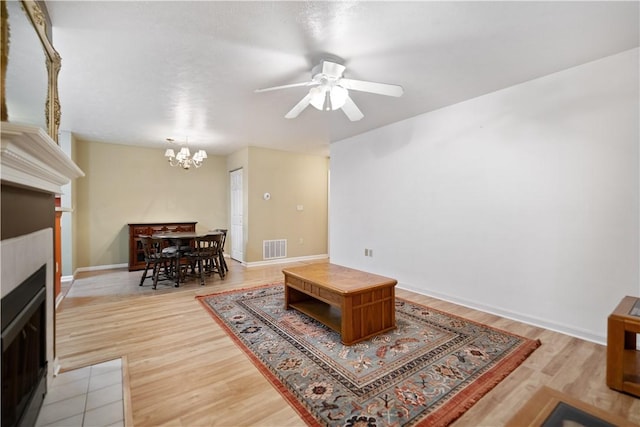 living room with light wood-type flooring and ceiling fan with notable chandelier