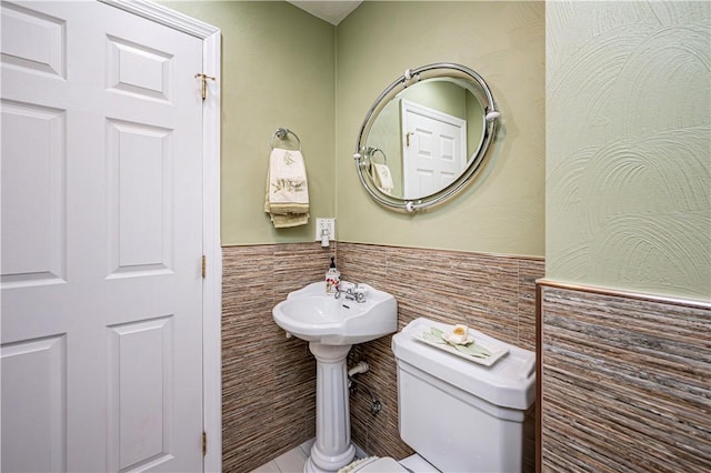 bathroom featuring toilet and tile walls