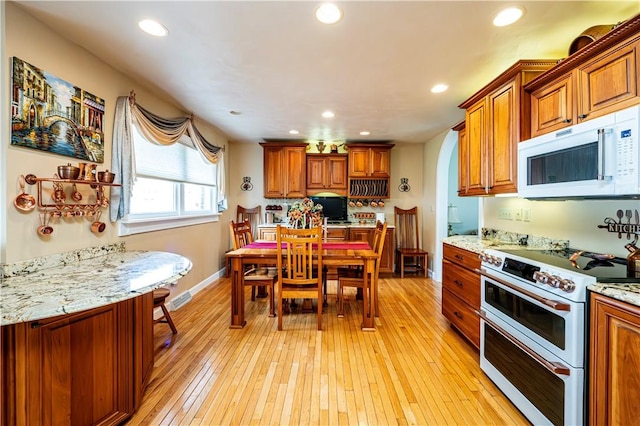 kitchen with light hardwood / wood-style floors, light stone counters, and electric stove